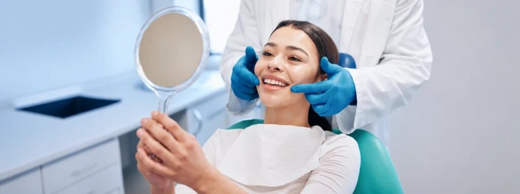 Patient viewing her smile in a hand mirror after cosmetic dental treatment in Dover, NJ